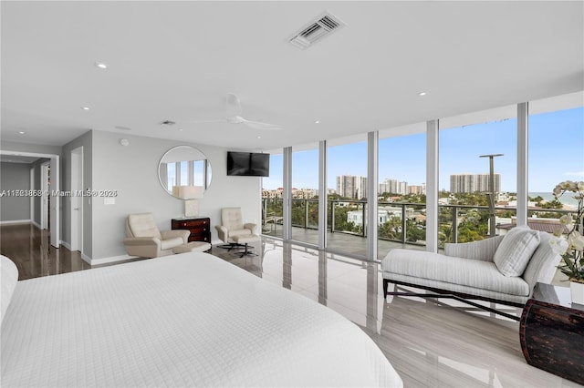 bedroom featuring multiple windows, ceiling fan, and a wall of windows