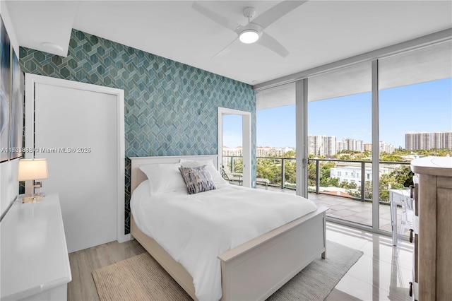 bedroom featuring expansive windows, ceiling fan, and access to outside