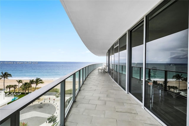 balcony featuring a water view and a beach view