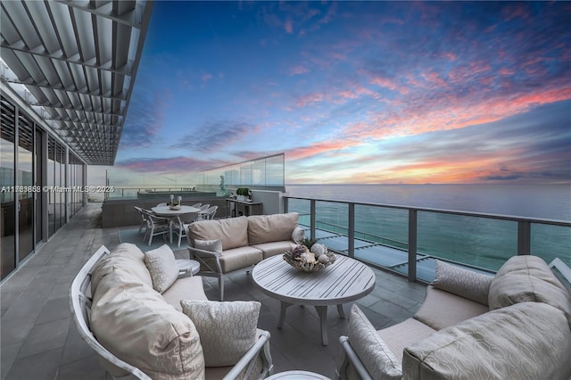 balcony at dusk featuring outdoor lounge area and a water view