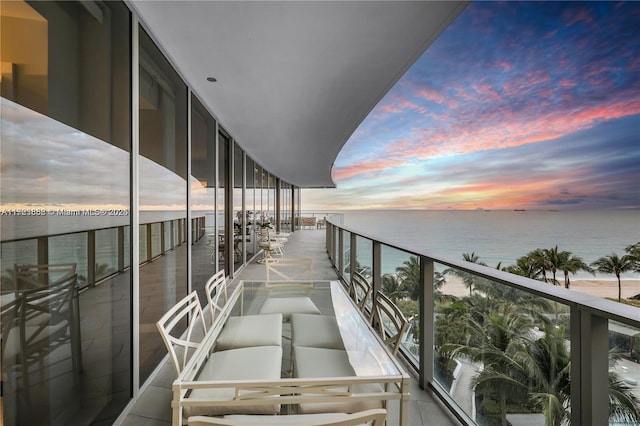 balcony at dusk featuring a water view