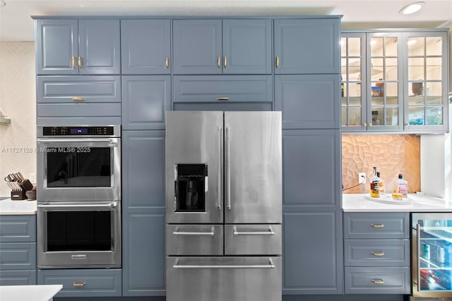 kitchen featuring stainless steel appliances, decorative backsplash, and beverage cooler