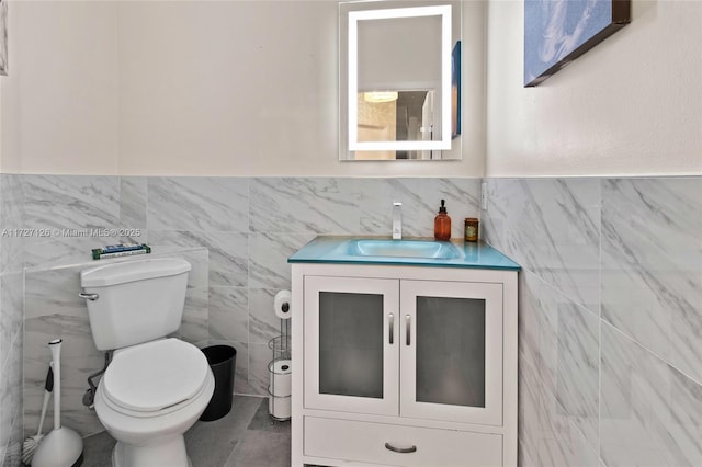 bathroom featuring tile walls, toilet, and vanity