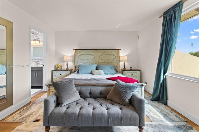 bedroom with light wood-type flooring and ensuite bathroom