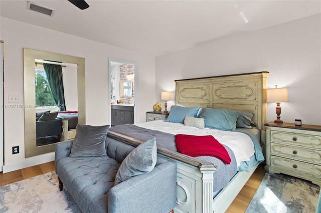 bedroom with light wood-type flooring, ceiling fan, ensuite bathroom, and multiple windows