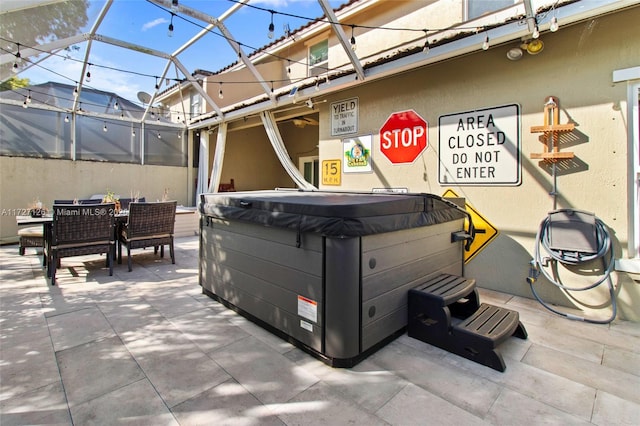 view of patio featuring glass enclosure and a hot tub