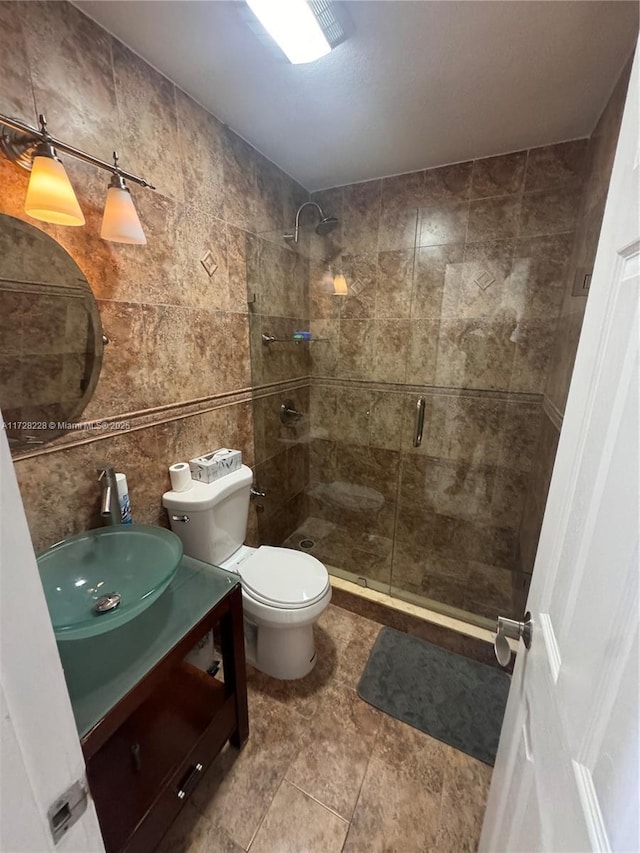 bathroom with toilet, tile walls, a shower with shower door, and vanity