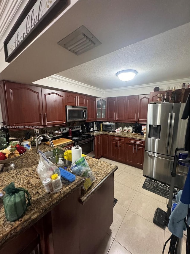 kitchen with dark stone counters, light tile patterned flooring, crown molding, and stainless steel appliances