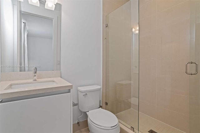 bathroom featuring toilet, a shower with door, and vanity