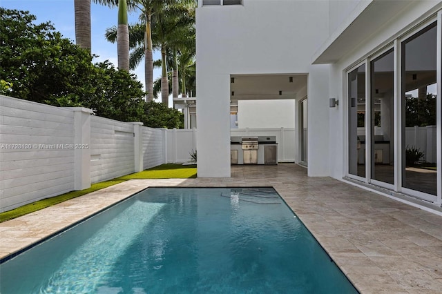 view of swimming pool featuring exterior kitchen, a patio area, and grilling area