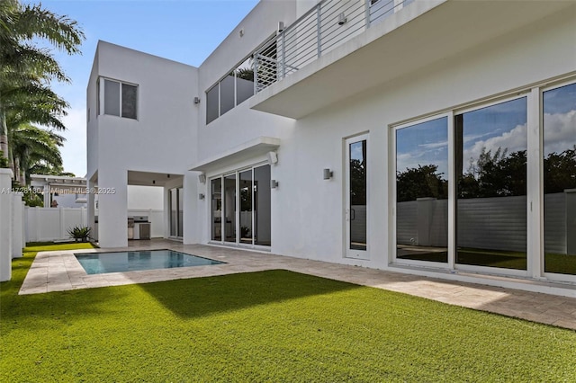 back of property with a fenced in pool, a lawn, and a patio