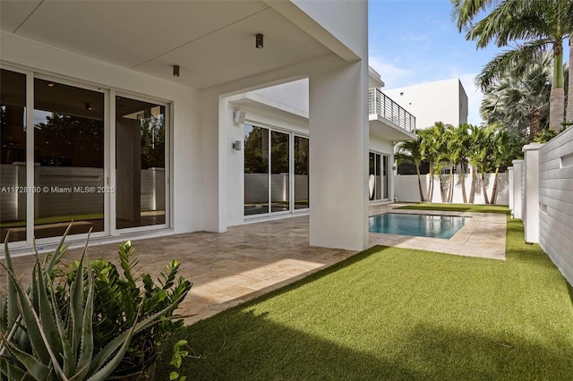 rear view of property featuring a fenced in pool and a patio