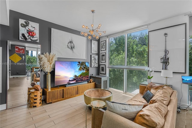 living room featuring expansive windows, a notable chandelier, and light wood-type flooring