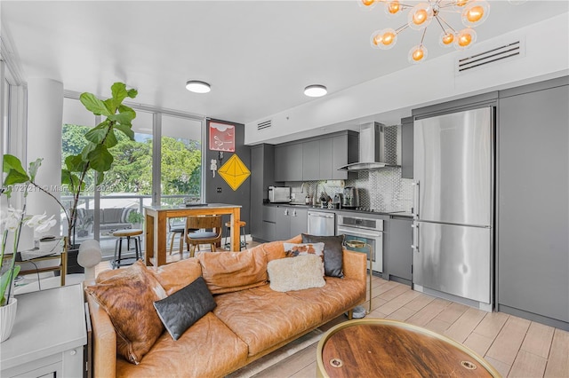 living room featuring light wood-type flooring, a notable chandelier, and sink