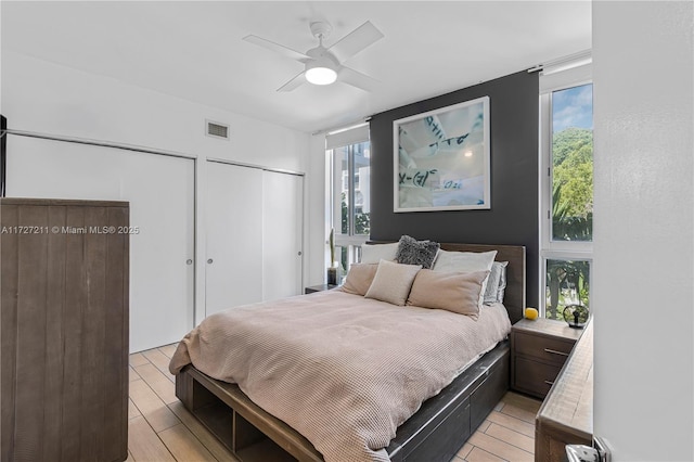 bedroom with ceiling fan and two closets