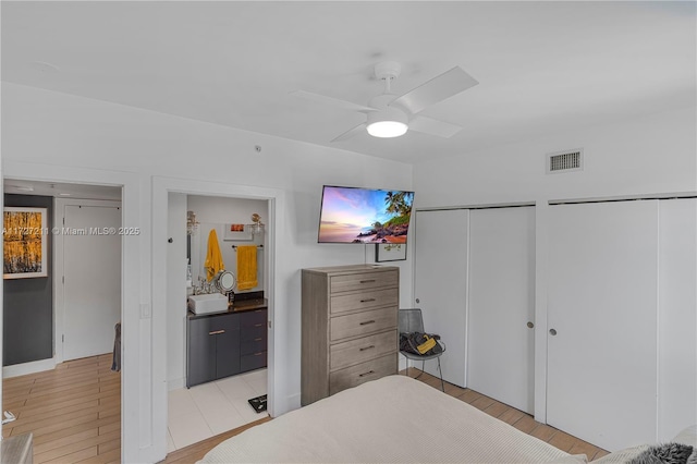 bedroom featuring ceiling fan, connected bathroom, light wood-type flooring, and multiple closets