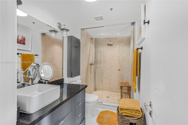 bathroom featuring toilet, tile patterned flooring, a tile shower, and vanity