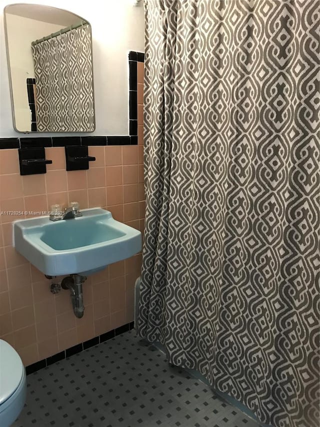 bathroom with sink, tile walls, toilet, and tile patterned flooring