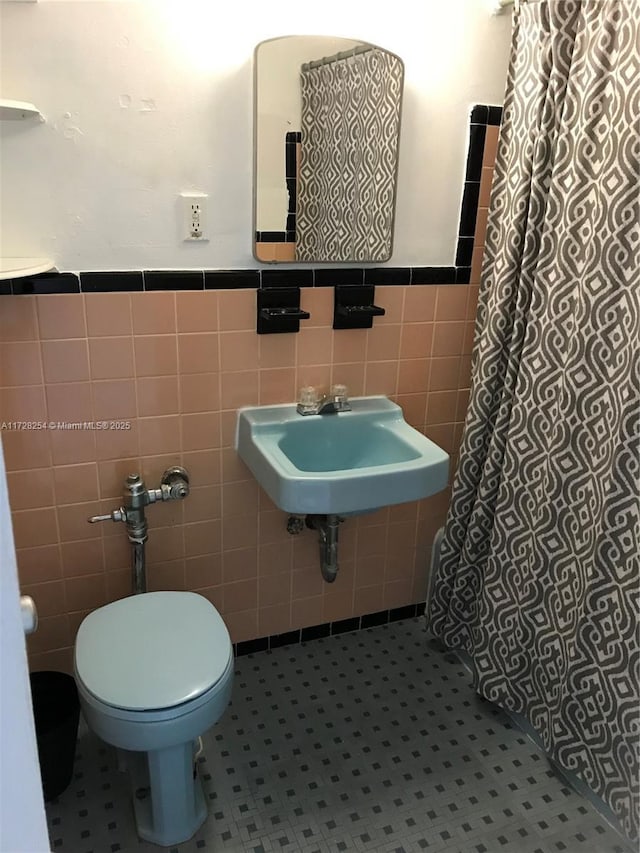 bathroom with toilet, tile walls, and tile patterned floors