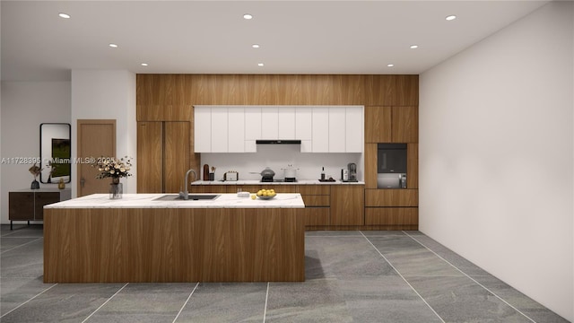 kitchen with stovetop, range hood, white cabinets, sink, and an island with sink