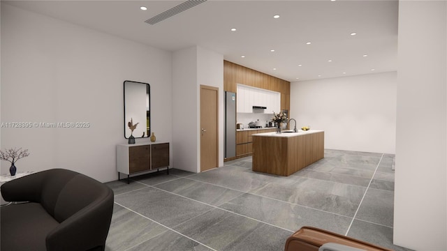 kitchen featuring sink, a center island with sink, and wood walls