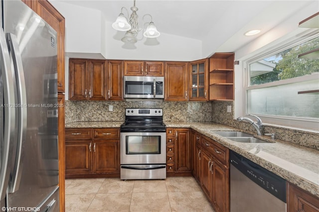 kitchen with pendant lighting, appliances with stainless steel finishes, lofted ceiling, sink, and light stone counters