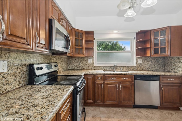 kitchen with ceiling fan, tasteful backsplash, sink, light stone countertops, and appliances with stainless steel finishes