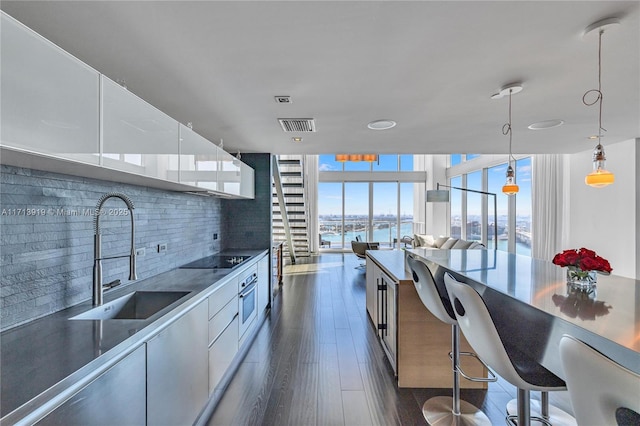 kitchen featuring floor to ceiling windows, sink, pendant lighting, and a water view