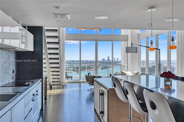 kitchen with white cabinetry, dark hardwood / wood-style flooring, decorative backsplash, a water view, and black electric cooktop