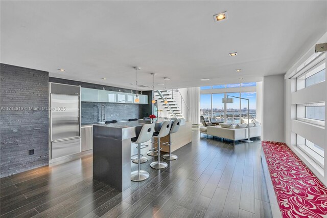 kitchen featuring pendant lighting, white cabinets, a center island, dark hardwood / wood-style flooring, and a breakfast bar area