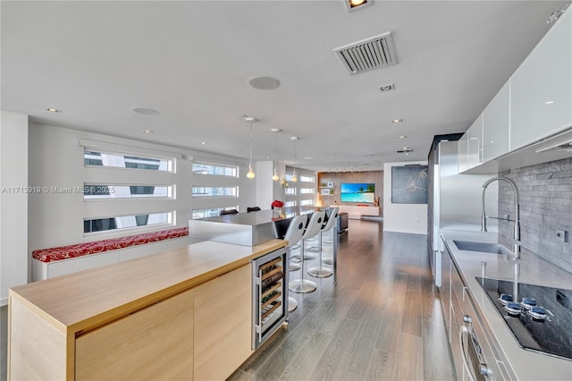 kitchen with pendant lighting, beverage cooler, black electric stovetop, sink, and dark hardwood / wood-style floors