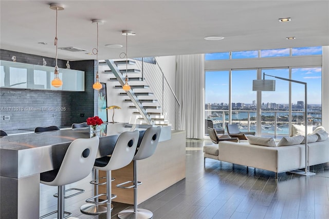 interior space featuring a kitchen bar, hanging light fixtures, and dark hardwood / wood-style floors