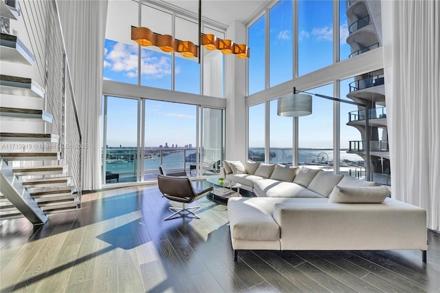 living room featuring hardwood / wood-style flooring, a towering ceiling, and a water view