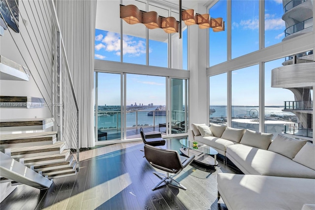 living room featuring a towering ceiling, hardwood / wood-style floors, and a water view