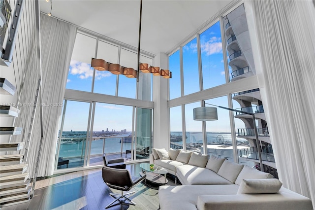 living room featuring plenty of natural light, a wall of windows, a water view, and hardwood / wood-style floors