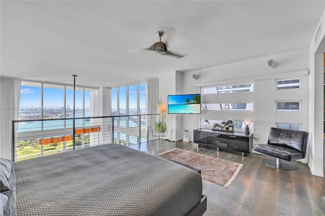 bedroom featuring dark wood-type flooring, ceiling fan, a wall of windows, and a water view