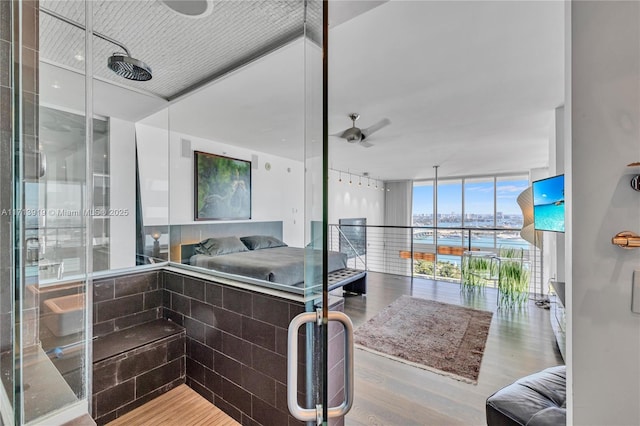 bathroom with ceiling fan, hardwood / wood-style floors, and a wall of windows