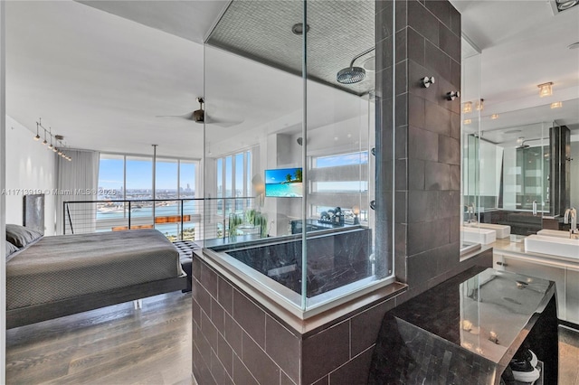 bedroom featuring ceiling fan, sink, floor to ceiling windows, and hardwood / wood-style floors