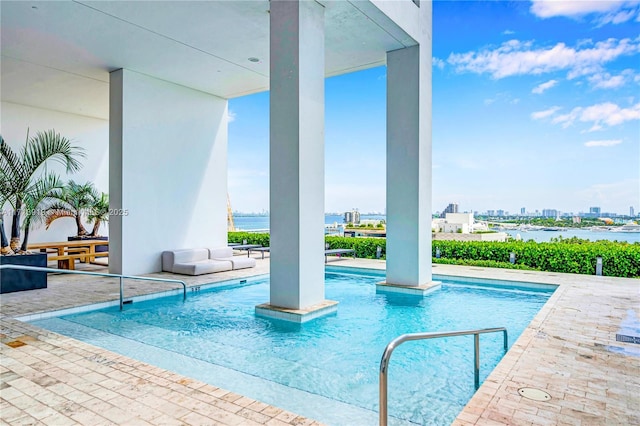 view of swimming pool with a water view and a patio