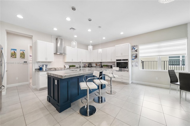 kitchen featuring wall chimney range hood, white cabinets, hanging light fixtures, and oven