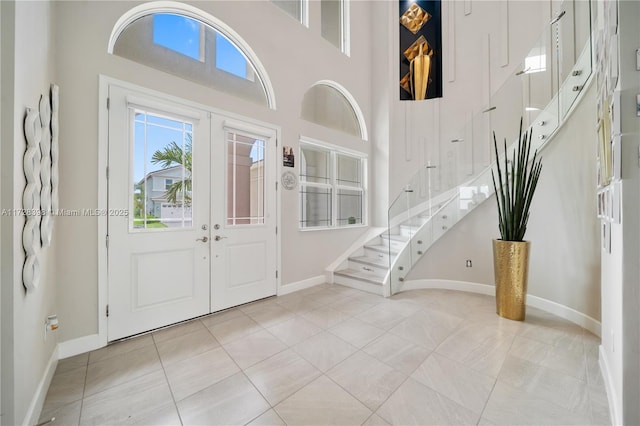 foyer entrance with a high ceiling, light tile patterned floors, and french doors