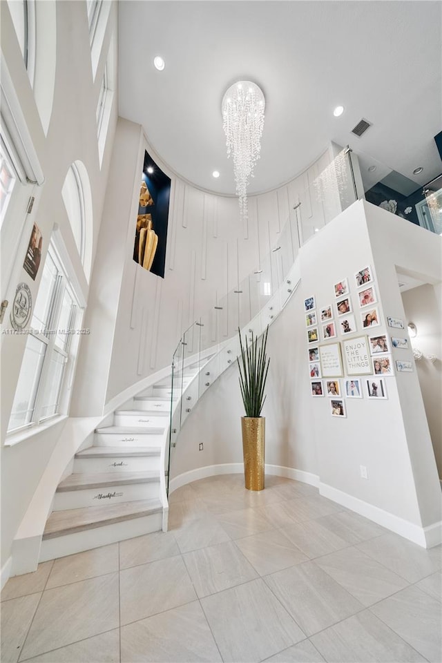 staircase with a towering ceiling and an inviting chandelier