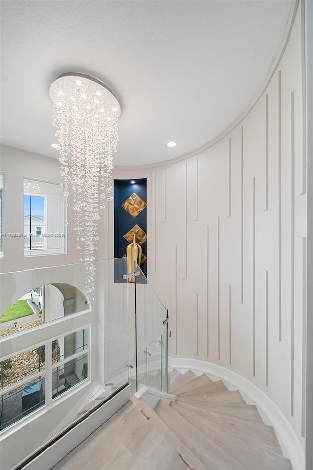 staircase featuring a baseboard heating unit and a notable chandelier