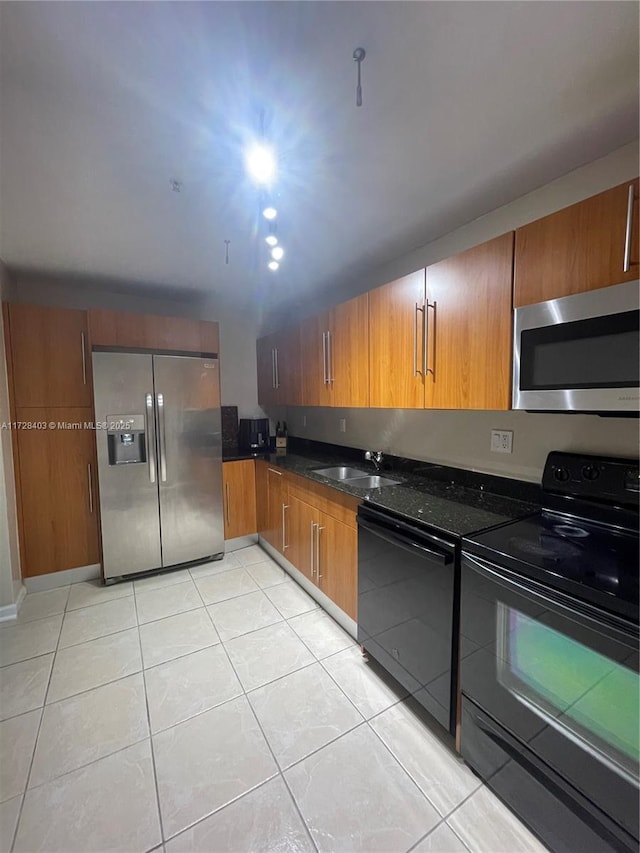 kitchen with sink, dark stone countertops, black appliances, and light tile patterned flooring