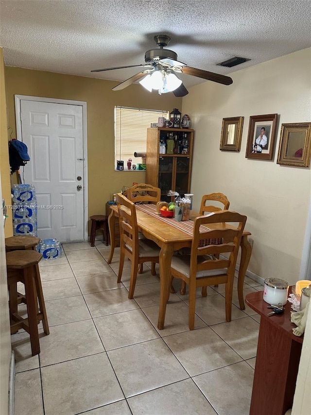 dining space featuring ceiling fan, light tile patterned flooring, and a textured ceiling