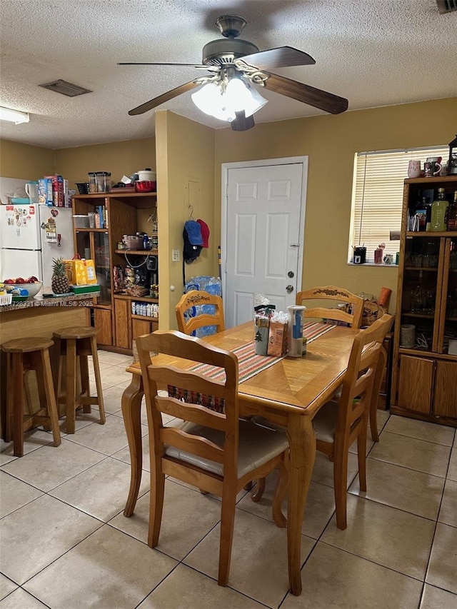 dining area featuring ceiling fan, a textured ceiling, and light tile patterned floors