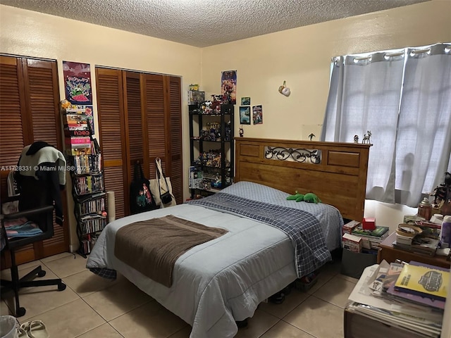 tiled bedroom featuring two closets and a textured ceiling