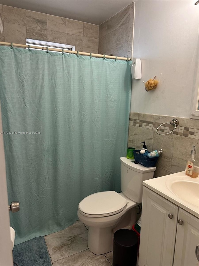 bathroom with tile patterned flooring, vanity, tile walls, toilet, and walk in shower