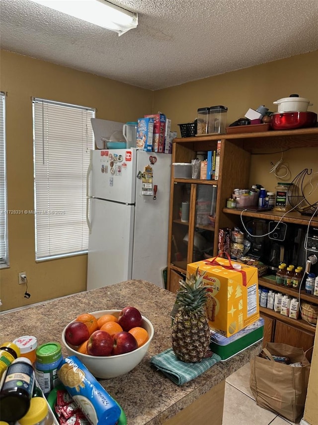 kitchen with a textured ceiling, white refrigerator, and tile patterned floors