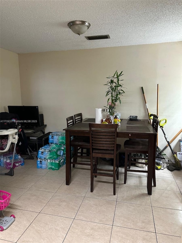 dining room with a textured ceiling and light tile patterned flooring